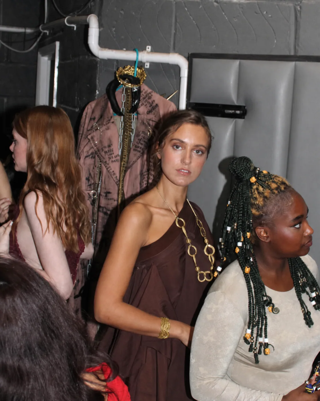 Modelo usando colar e pulseira dourados da Moikato nos bastidores de um desfile
