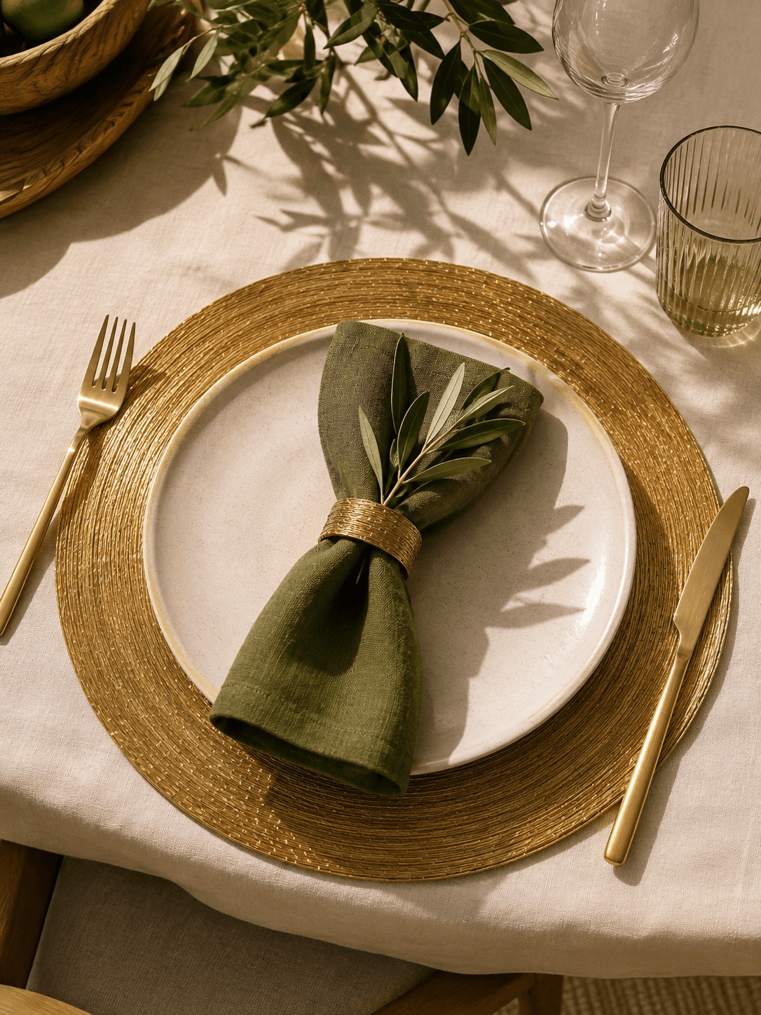 Sousplat Dourado artesanal compondo uma mesa com louça clara e guardanapo verde