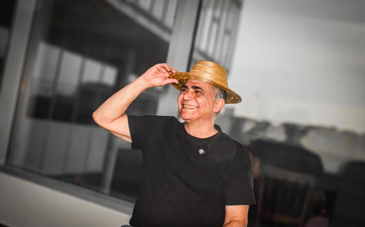 Samuel Moikato sorrindo e usando um chapéu artesanal de fibras naturais